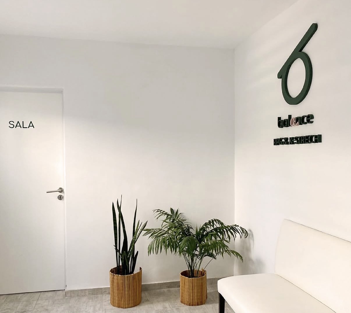 Espacio real de Balance: sala luminosa, plantas y banco blanco junto al logo del estudio